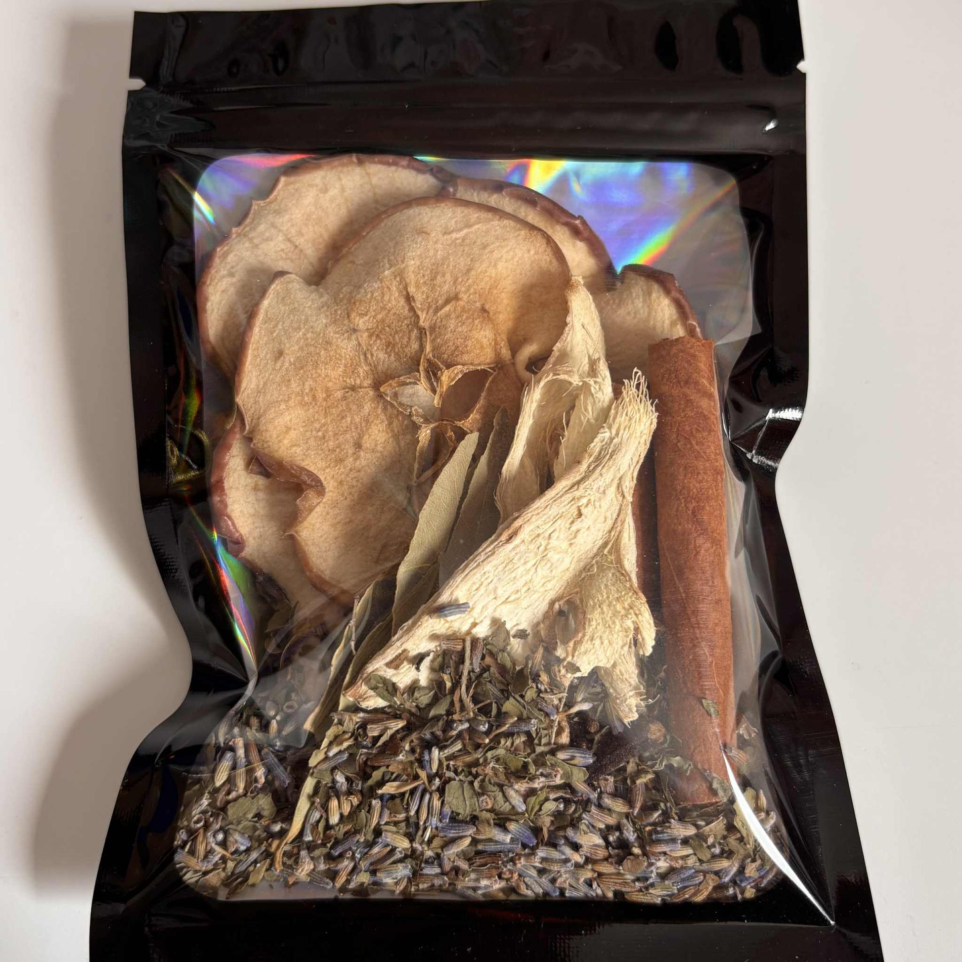 Black packaging with a clear window displaying dried herbs and fruit.